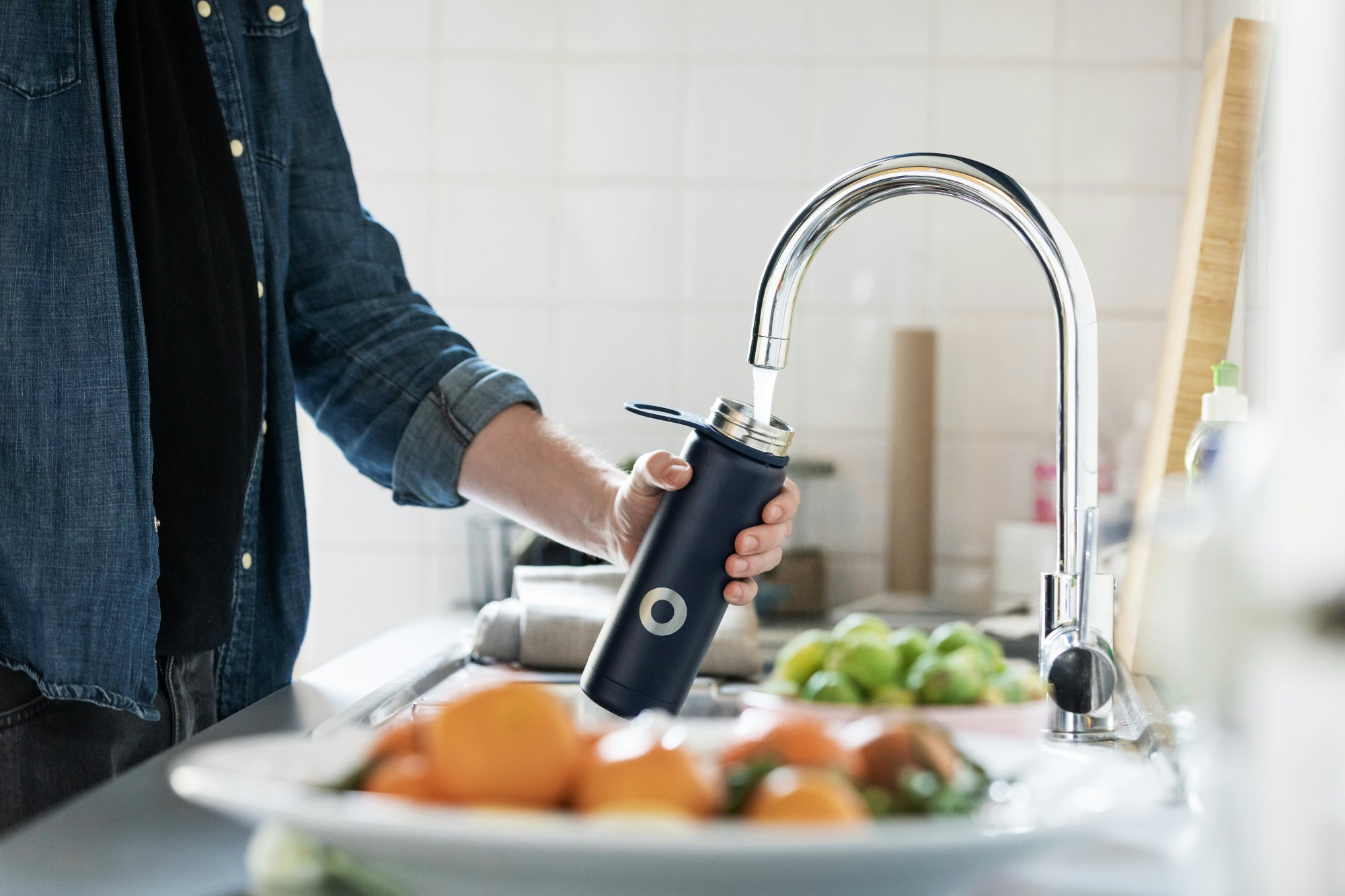 Filling a reusable water bottle from a kitchen tap