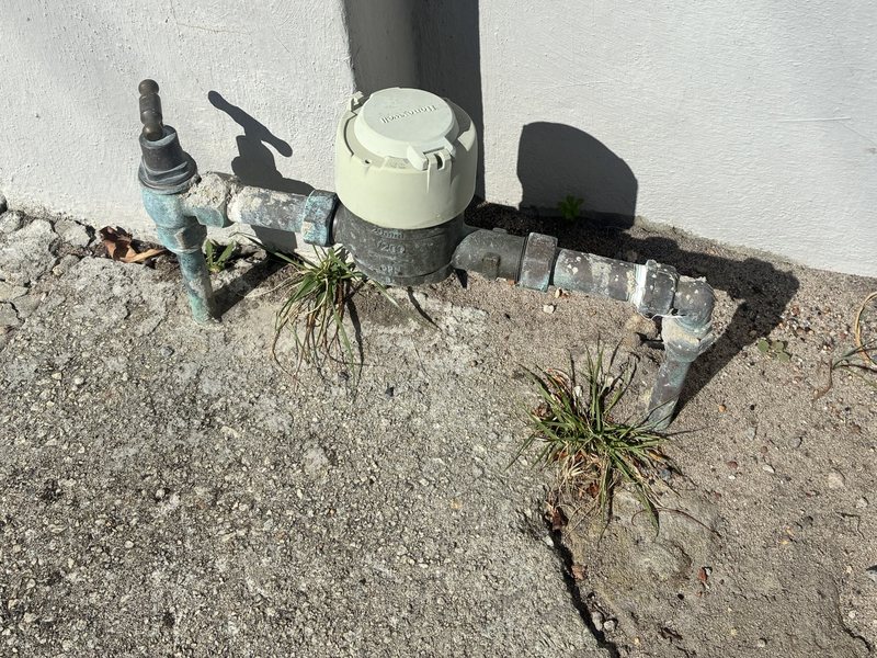 A typical Perth water meter: a small grey meter with a cream cap on the pipe at the base of a wall, with a tap beside it