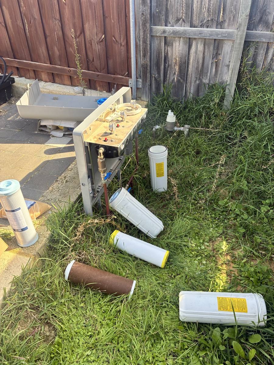 Used filter housings and cartridges laid out beside an opened whole-home filtration unit during a service visit